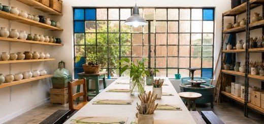El espacio de Vamos al Taller: mesa larga, estantes con piezas y ventanal